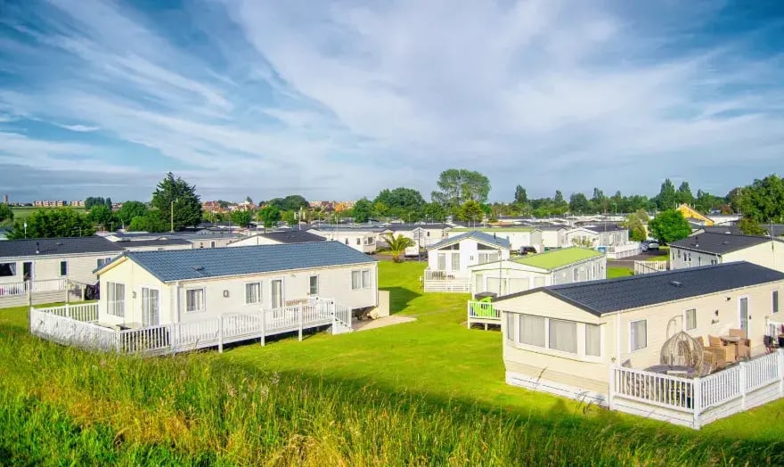 A group of static caravans set up on grass with showers cubicles inside them.