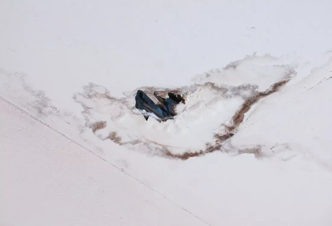 A ceiling with a hole caused by a leaking shower above.