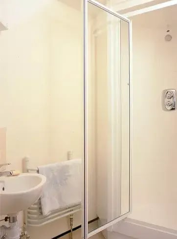 A freestanding shower cubicle being used in a bathroom with limited space.