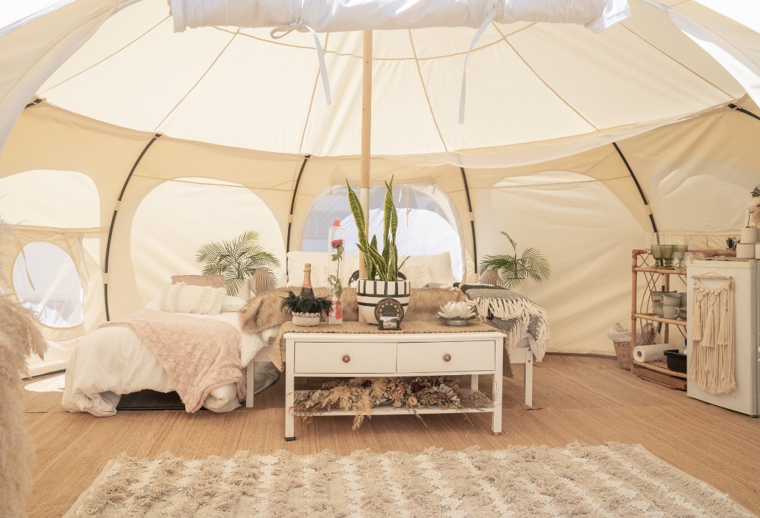 A nicely decorated luxury yurt with a bed and associated furniture.