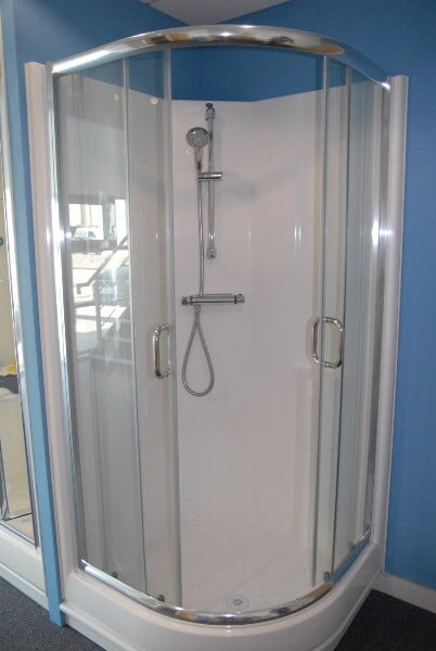 A modern waterproof shower cubicle with glass sliding doors and integrated shower fittings.