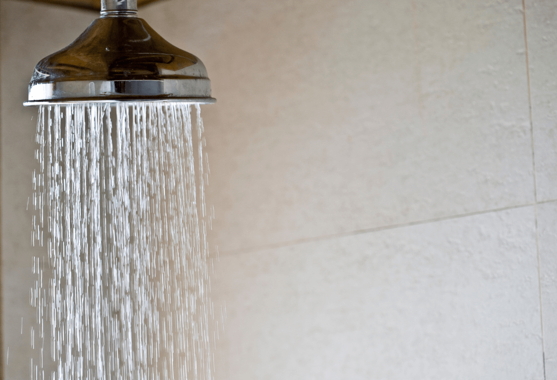 A shower head being used in the bathroom by a homeowner.