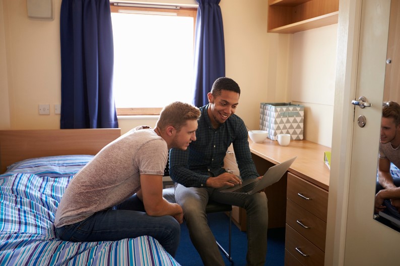 Two students sitting in their University Halls, which have en-suite shower pods.