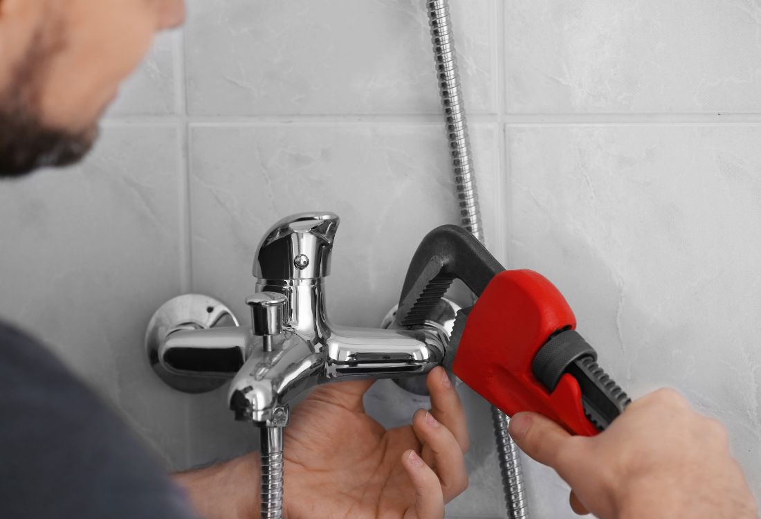 A plumber fixing a shower saving a residential landlord extra costs as a result of neglect.  
